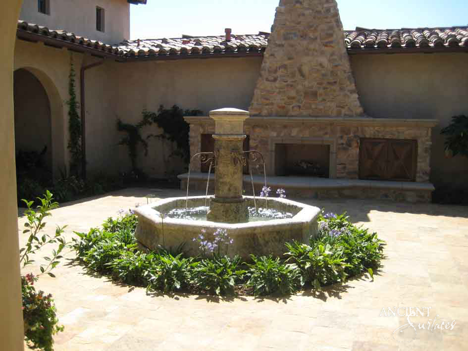 Octagonal limestone pool fountain with a flowing pillar spout in a Mediterranean courtyard